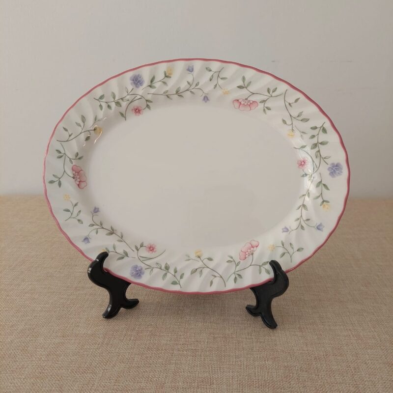 Vista frontal de una fuente ovalada festoneada de loza inglesa Johnson Brothers, patrón Summer Chintz, decorada con guirnaldas de flores silvestres rosa, lila y amarillo.