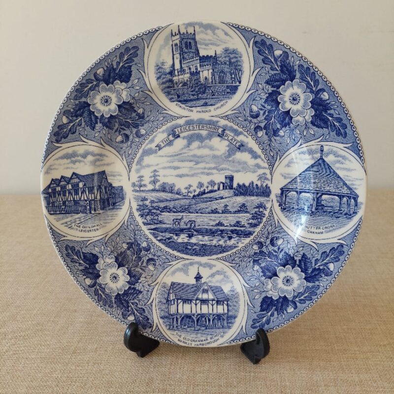 Vista frontal de un plato de colección de loza inglesa Weatherby Royal Falcon, titulado "The Leicestershire Plate", con grabados en azul cobalto de monumentos históricos