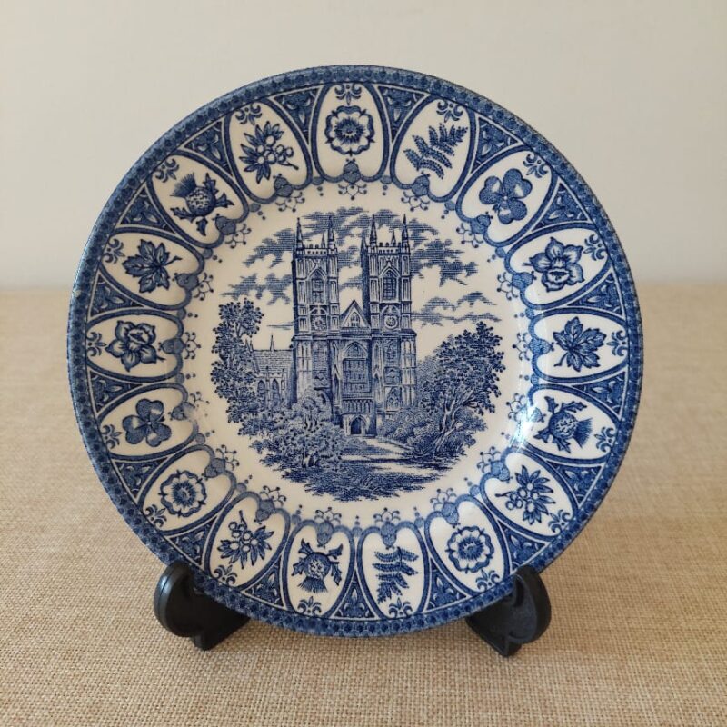 Vista frontal de un plato de postre vintage de loza inglesa Broadhurst, edición Jubileo de Plata 1977, con el grabado azul cobalto de la Abadía de Westminster y bordes de emblemas reales.
