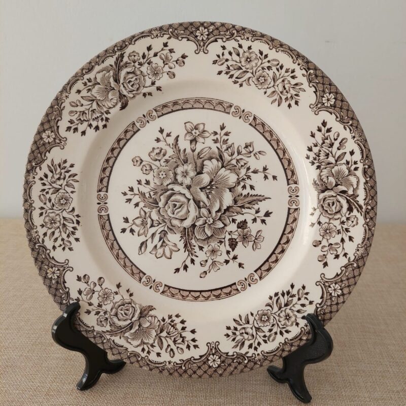 Vista frontal de un plato principal de loza crema inglesa Staffordshire Tableware con un intrincado diseño transferware marrón de rosas y ramos de flores.