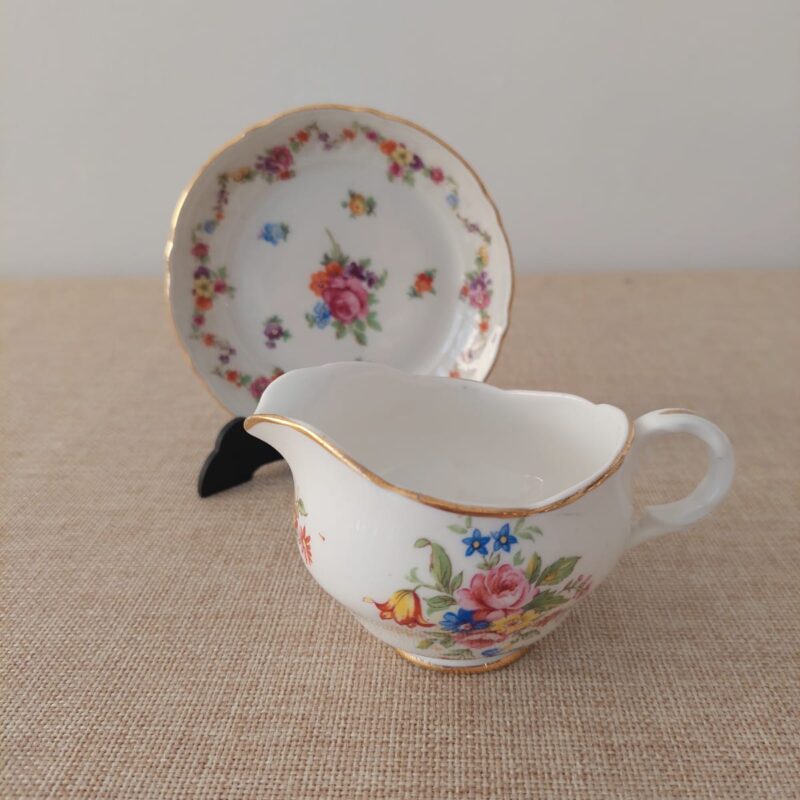 Set decorativo de porcelana fina Schumann Bavaria compuesto por un despojador circular de 10 cm y un mini cremero con diseño floral y bordes de oro.