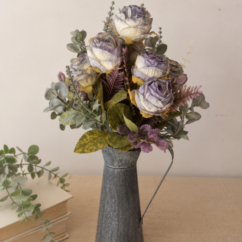 Arreglo floral permanente en tonos lavanda envejecido, marfil y verde salvia presentado en jarrón metálico vintage, ideal para decoración elegante y acogedora.