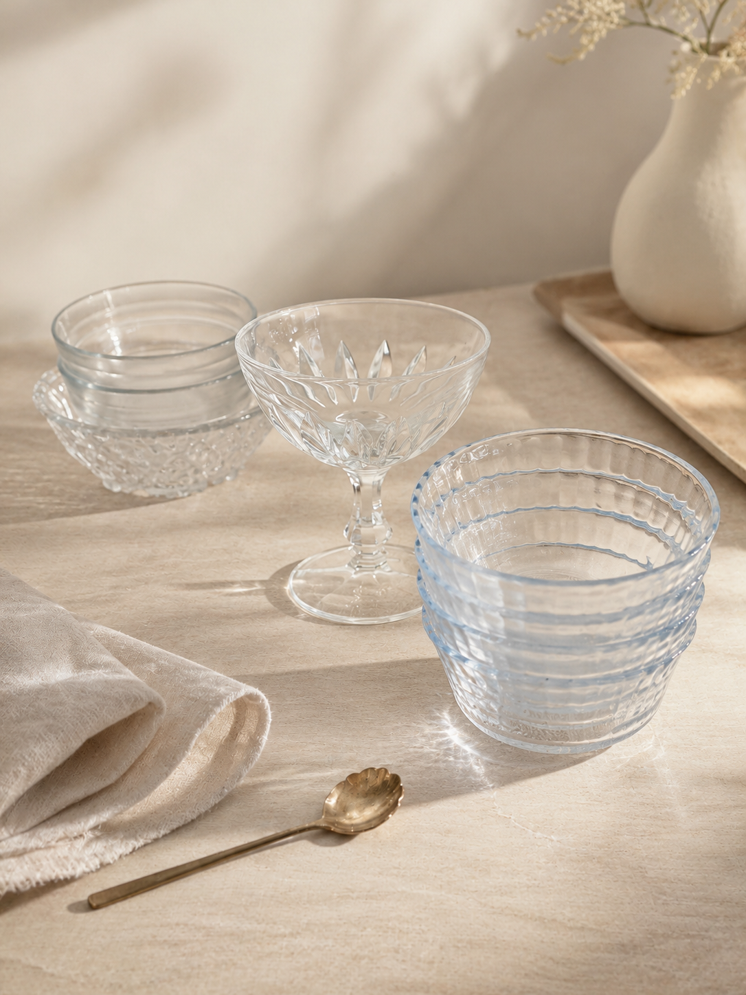 Colección de ocho piezas de vidrio compuesta por cuatro pocillos transparentes, dos recipientes de vidrio esmerilado, una copa tallada y un cuenco decorativo.