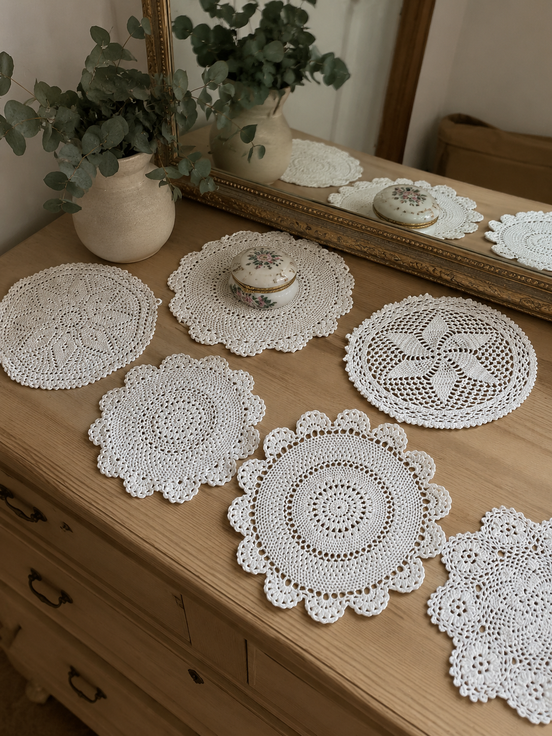 Set de siete tapetes decorativos tejidos a crochet artesanal en color crudo, con diferentes diseños circulares y florales, ideales para decoración de mesas y muebles.