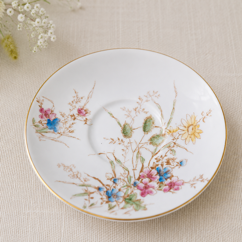 Plato de té Crown Staffordshire Fine Bone China con delicado diseño de flores silvestres en tonos pastel y borde dorado.