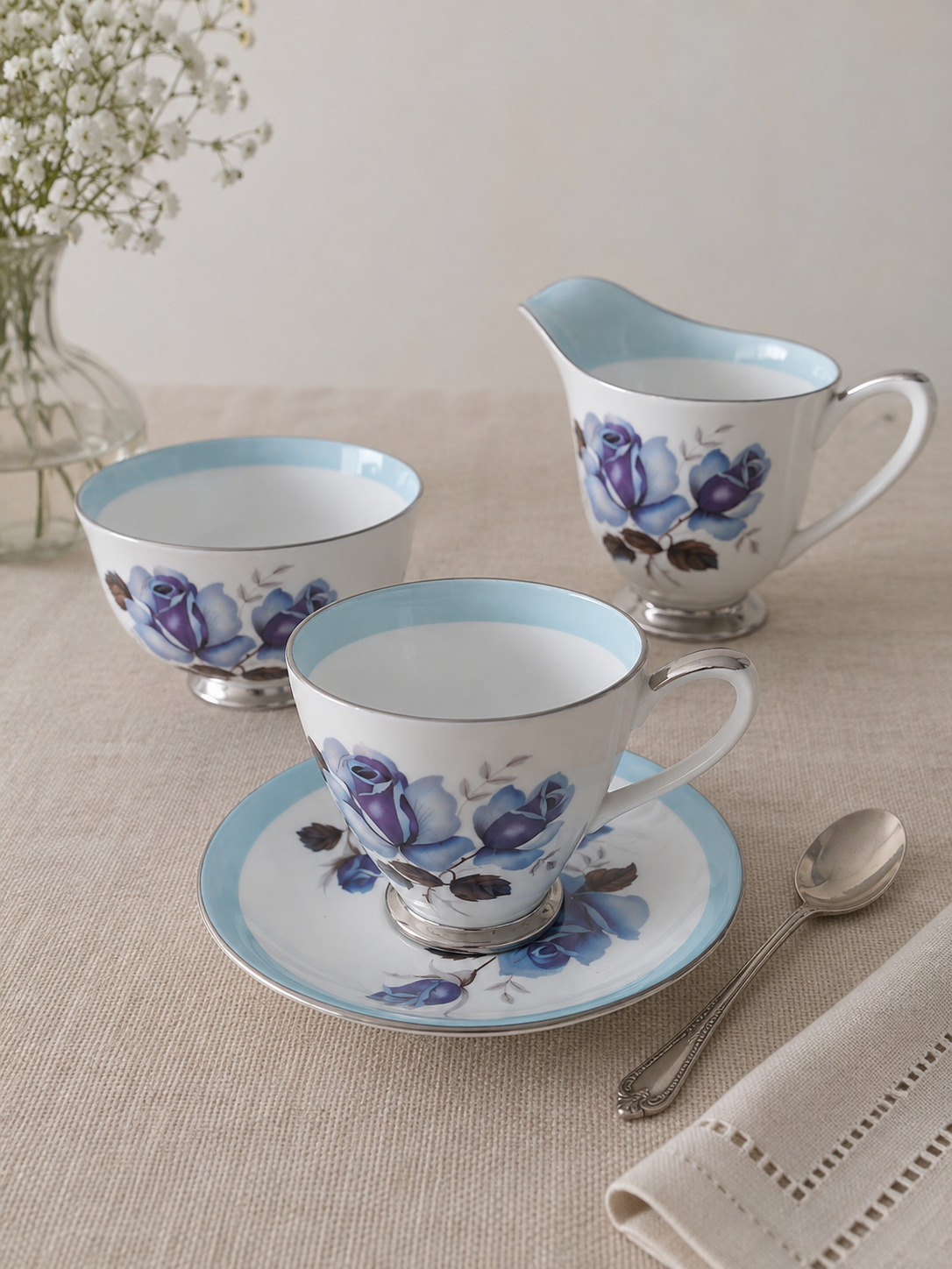 Colección vintage Windsor Bone China Made in England con dúo de té, lechero y terronero decorados con rosas azules, borde celeste y terminaciones plateadas.